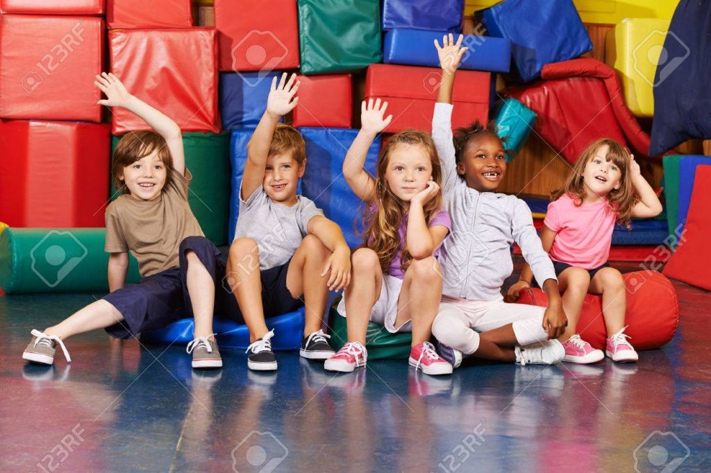 38202025-happy-children-raising-their-hands-in-gym-of-an-elementary-school.jpg